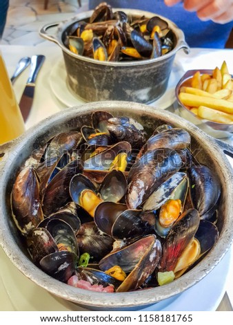 Mussels in roquefort sauce and French fries, national traditional Belgian dish served with beer  in a restaurant in the center Brussels.