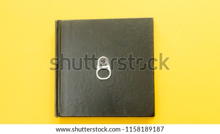 black notebook with can opener symbol on yellow background