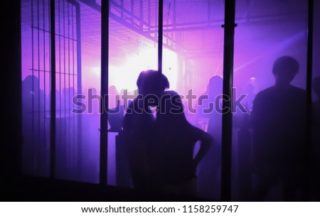 Silhouetts of young couple in the club with purple scenic illumination