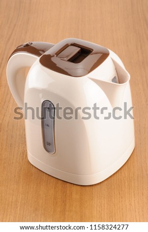 Beige and brown color plastic cordless electrical kettle on the wood background
