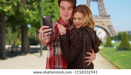 Loving young couple take fun selfies in front of the Eiffel Tower