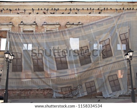 The facade of the house is closed with a protective cloth during the repair. A banner shows the facade of the house. protective cloth as a curtain in the theater