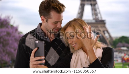 Joyful newly engaged couple take a selfie in Paris