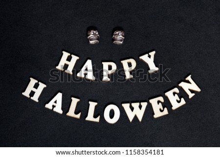 Happy Halloween - inscription on a black background. Wooden words and two skulls for decoration on the day of all the saints.