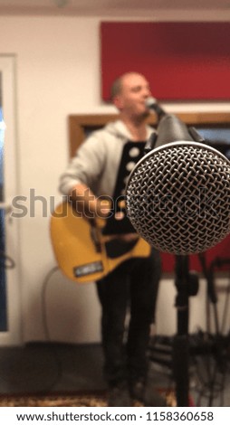 close-up of microphone with guitarist in the background