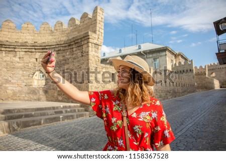 Happy tourist girl taking a selfie in old town street. Tourist concept.