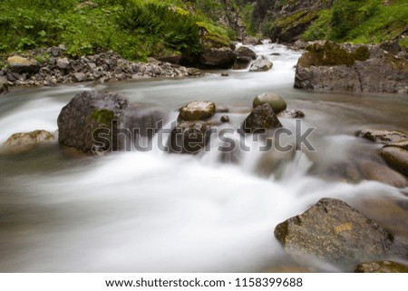 The stream of water in the river flowing between the rocks in the mountains national park. Long exposure.
