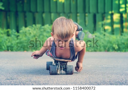 A little boy skates near a house on the road.