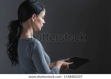 Young woman using her tablet on a gray background