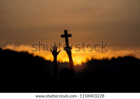 Lift and holding christian cross with light sunset background. silhouette concept