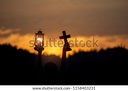 Children holding oil lamp and christian cross with light sunset background. silhouette concept
