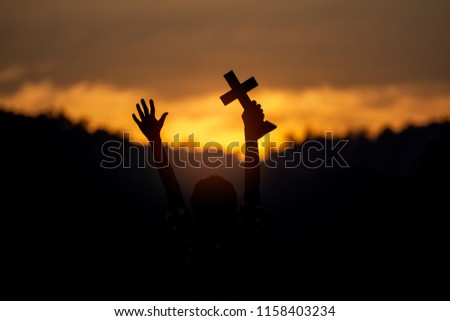 Children holding christian cross with light sunset background. silhouette concept