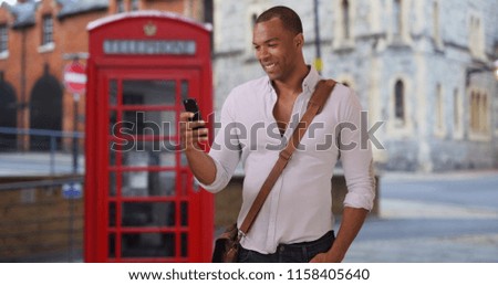 African male tourist in England sending pictures and messages on phone 