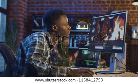 Side view of black man working on computer and editing video with color correction