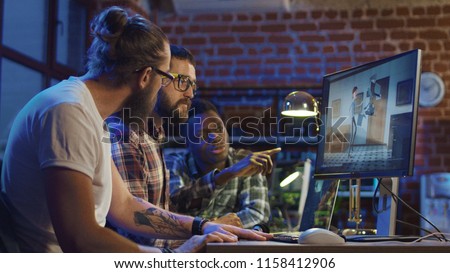 Side view of diverse group of men sitting at table with computer and coworking on creation of new cartoon Royalty-Free Stock Photo #1158412906