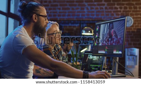 Young man and girl in glasses sharing ideas and working on video editing on computer doing montage and color correction