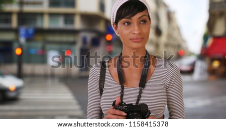 Young African woman shooting photographs in the city