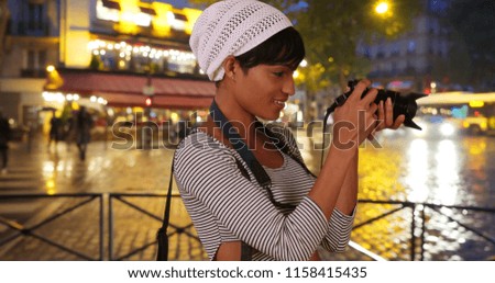 Creative young black woman photographing urban nightlife on digital camera