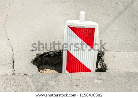 Street reconstruction or construction barricade traffic danger caution sign cover the open hole of damaged and cracked asphalt on the broken road as a precaution close up