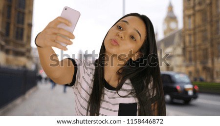 Happy smiling Colombian female taking selfies to post on social media in London