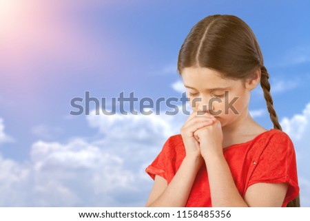 little girl praying on sky background