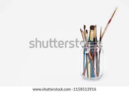 Worn paintbrushes in a glass jar