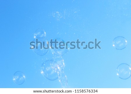 An artistically enhanced and manipulated photograph of a group of bubbles floating through the air in front of a blue background. 