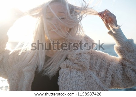 Lifestyle portrait of young blonde woman at sunset with sea background