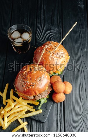 homemade juicy burgers on wooden board,  cheese balls. Street food, fast food.  with French fries and glass of  cola. top view