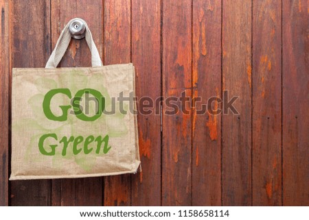 Go green logo on Jute bag hanging on old wooden door background, business sale concept