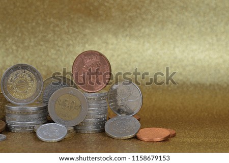 stacks of coins from different nations with Euros and Cents in front of golden background with copy space to the right