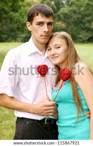 couple holding red heart on a stick