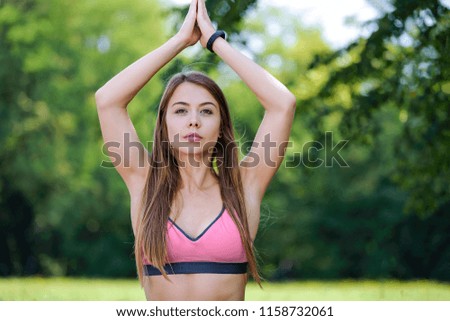 Portrait of attractive and young woman doing outdoors yoga meditation in a park on a sunny day