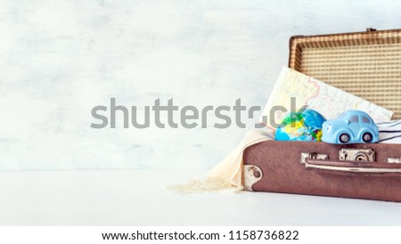 Travel, adventure, vacation concept. Brown retro suitcase with traveler set of travel booklets, maps, camera, clothes and blue toy car. How to Pack a Suitcase. Explore: Adventure Travel Holidays Royalty-Free Stock Photo #1158736822