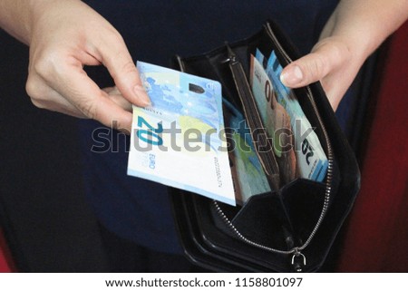 Female hands hold an open purse with money. There are a lot of bills in wallet. Salary. Finance concept