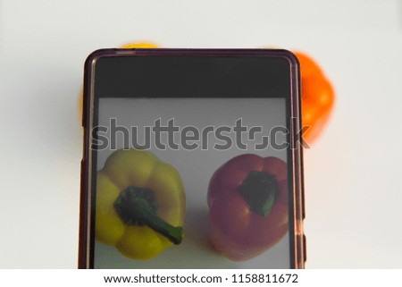 telephone camera photoshooting process. food photography concert. top view on pair of two bulgarian bright colorful peppers through phone screen background. vegetarian healthy nutrition wallpaper.