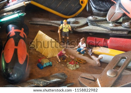 Miniature people figures camping in a pile of woodworking tools.. Macro photo