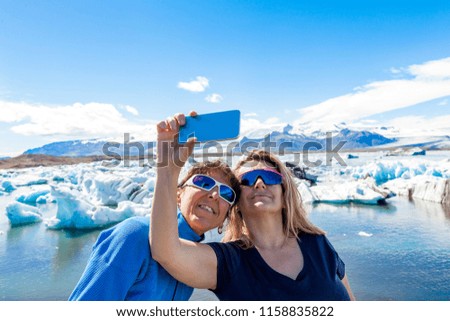 two female tourists taking a selfie with a smart phone in the icebergs lagoon of jokulsarlon