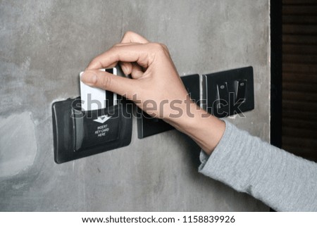 Closeup women hand insert key card to opening light electronic in hotel room.