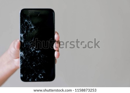 Hand holding Broken screen cell phone.
Using Smartphone Insurance and Mobile phone warranty concept.