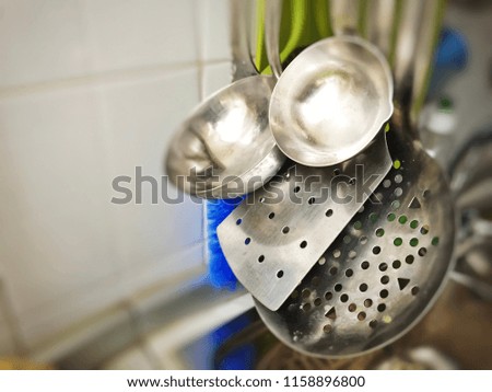 Steel ladles and colander hanging in a kitchen
