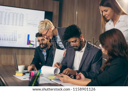 Group of business people working in an office, executive signing a contract. Focus on the businessman signing the contract