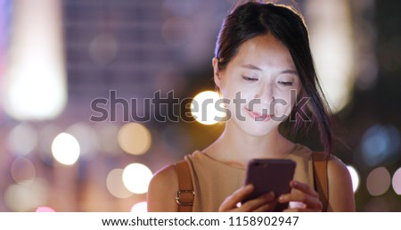 Woman sending sms on cellphone at night