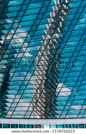 Geometry and lines of a modern business center. Clouds and buildings are reflected in the glass windows of the high-rise skyscraper of the modern commercial city of the future.