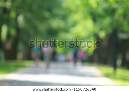 People in a green summer alley park bokeh blur background