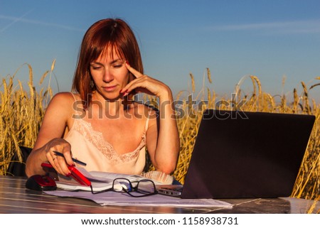 Young successful business lady is doing her own business where she wants. Workplace in the middle of the field