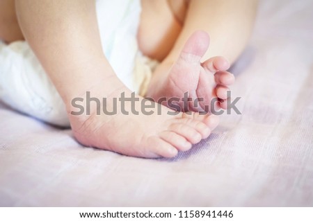 Tiny feet of a newborn baby girl on a gentle pink background. One week old infant baby. First days of her life image.