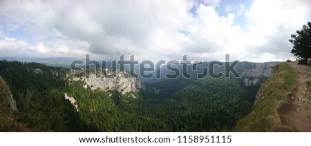 Majestic cloudy panorama of Creux-du-Van natural amphitheater in a foggy gloomy Summer mood - Switzerland