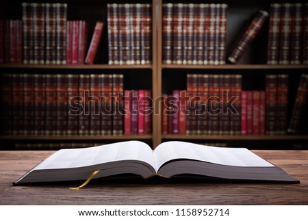 Close-up Of An Open Law Book On Wooden Desk In Courtroom
