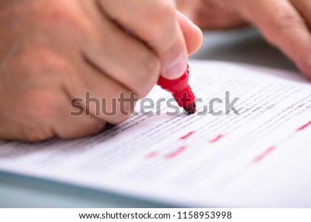 Close-up Of A Businessperson's Hand Marking Error With Red Marker